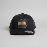 Black cap with a brown leather patch on a gray background