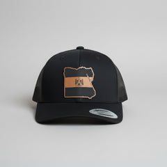 Black cap with a brown leather patch on a gray background