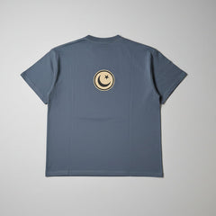 Blue t-shirt with a circular emblem on the back against a gray background