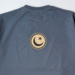 Blue t-shirt with a circular emblem featuring a moon and star on a white background