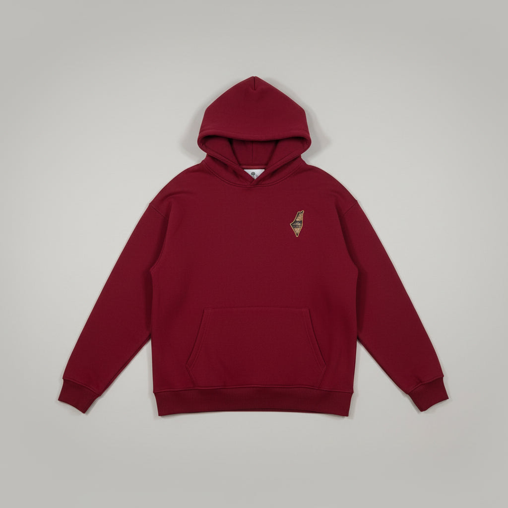 A red pullover hoodie with a small embroidered logo on the left chest, laid flat on a white sheet. The bottom of a person's legs wearing gray sweatpants and leopard-print slippers are visible at the bottom edge.